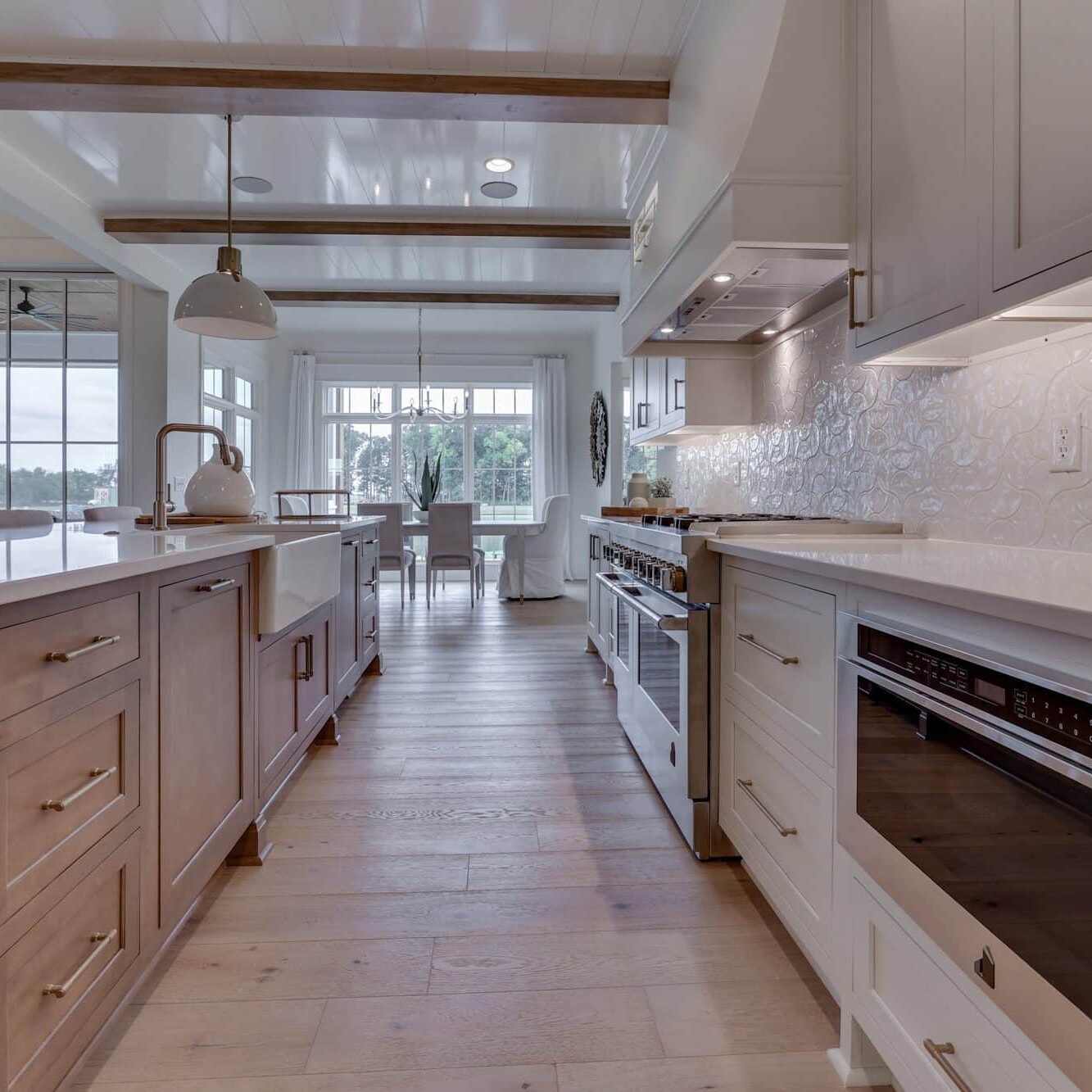 A kitchen with white cabinets and wood floors.