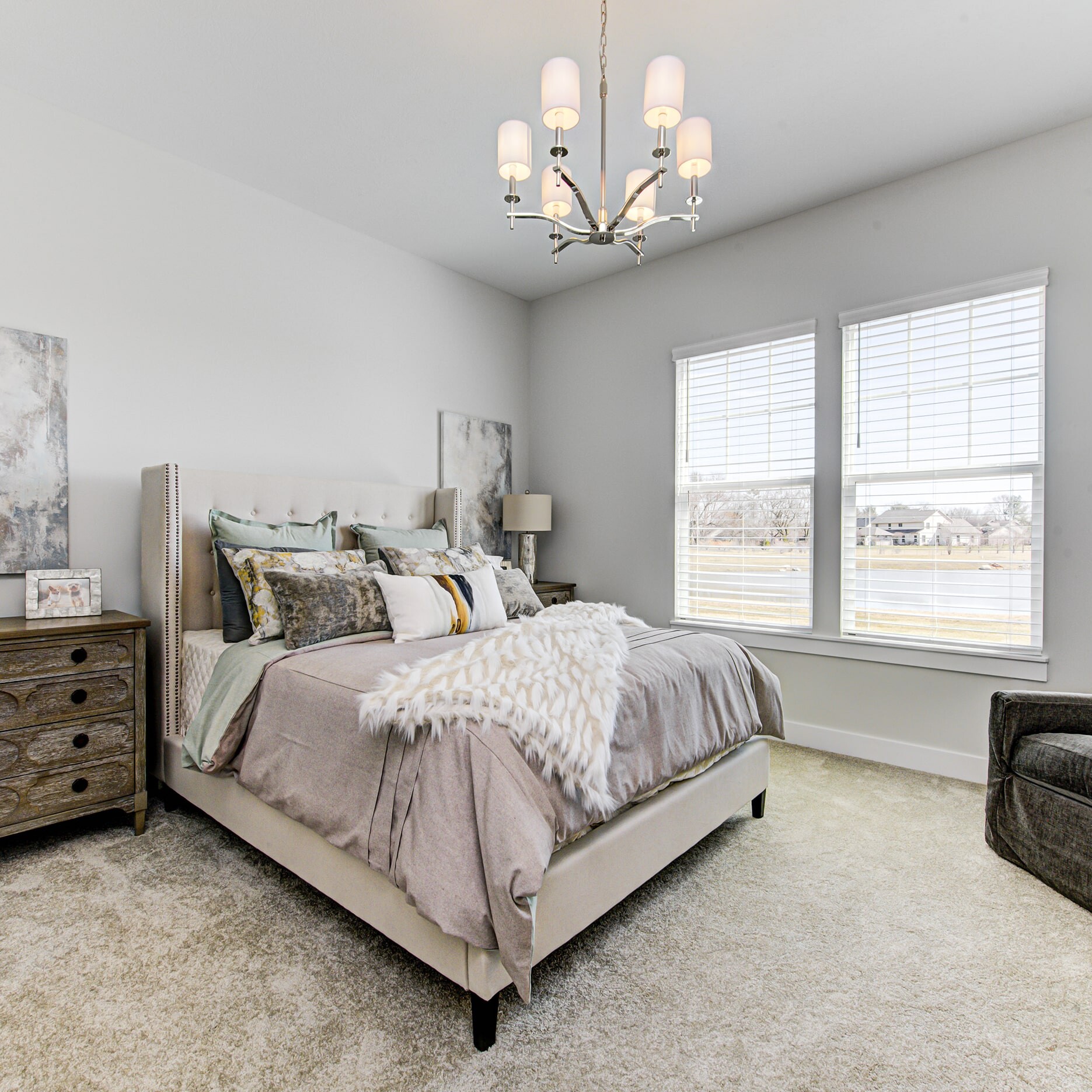 A bedroom with a bed, dresser and chair.