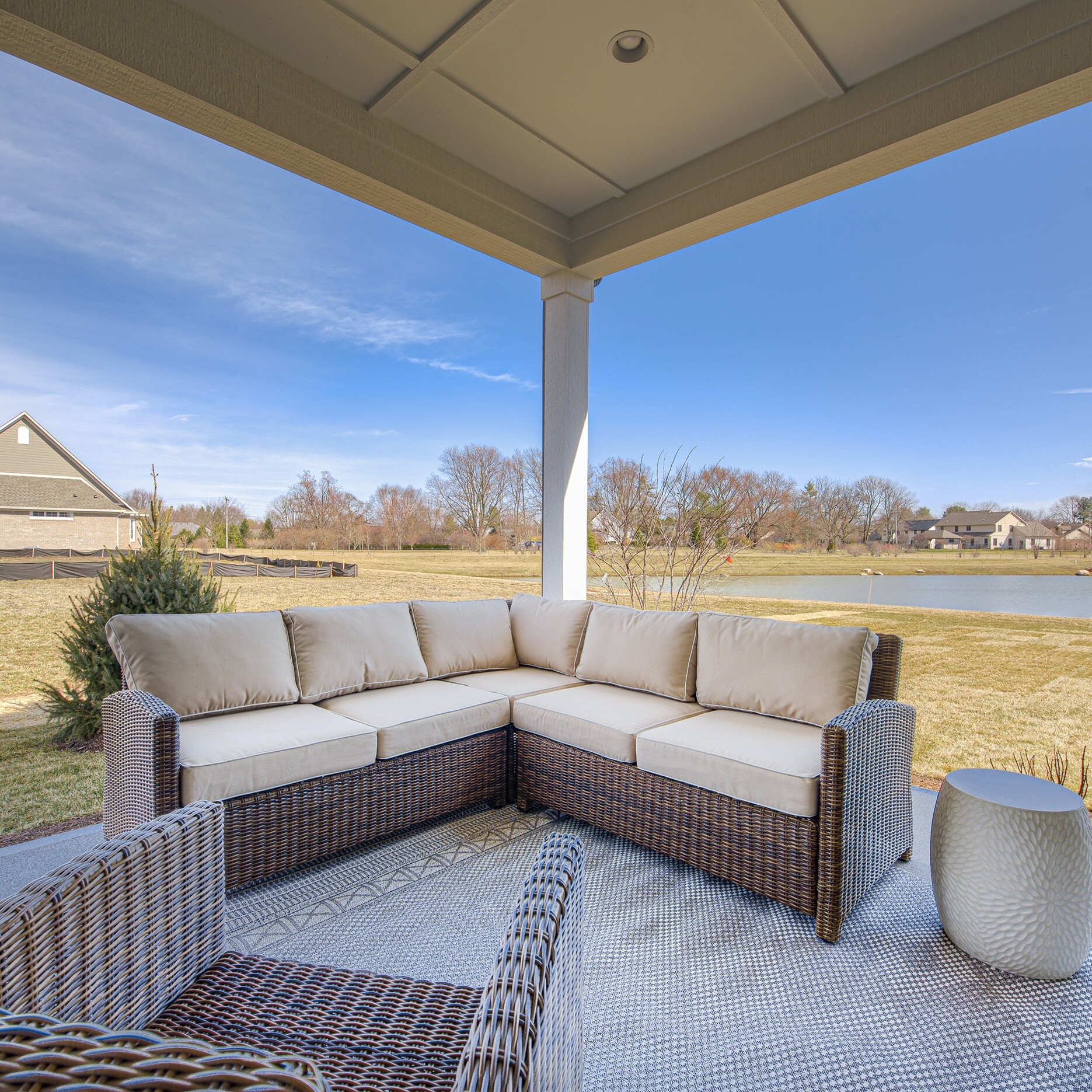 A patio with wicker furniture and a view of a pond.