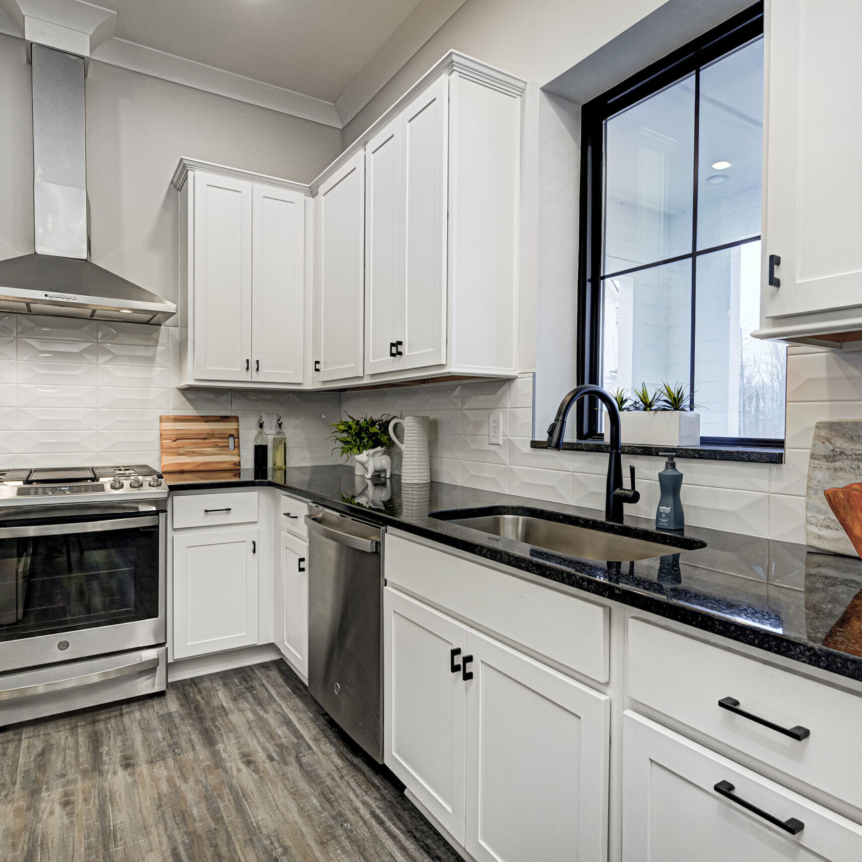 A custom kitchen with white cabinets and black counter tops.