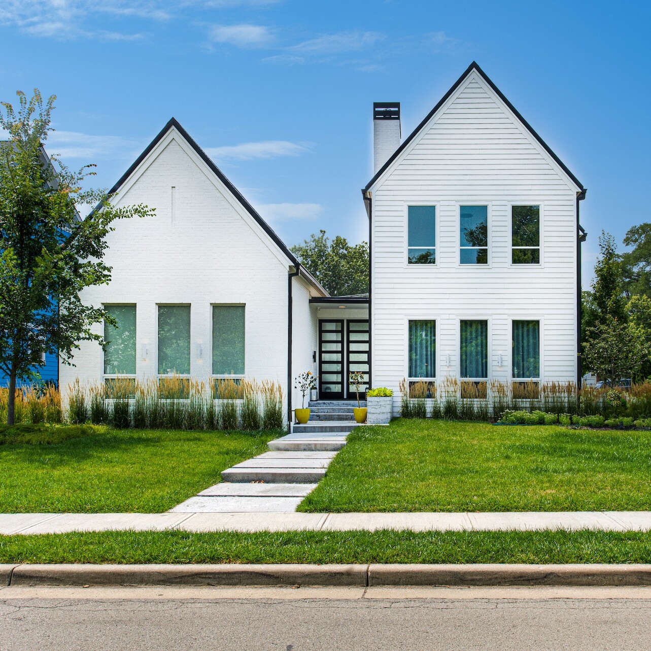 A white and blue house in the middle of a neighborhood.
