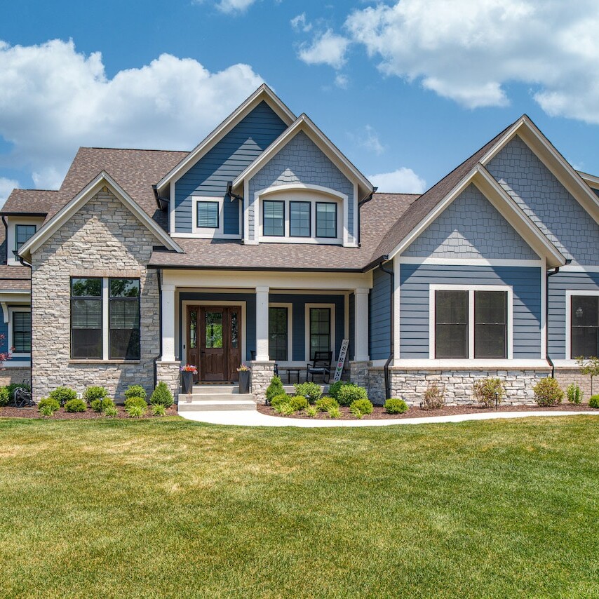 A custom home with blue siding and a grassy yard in Westfield, Indiana.