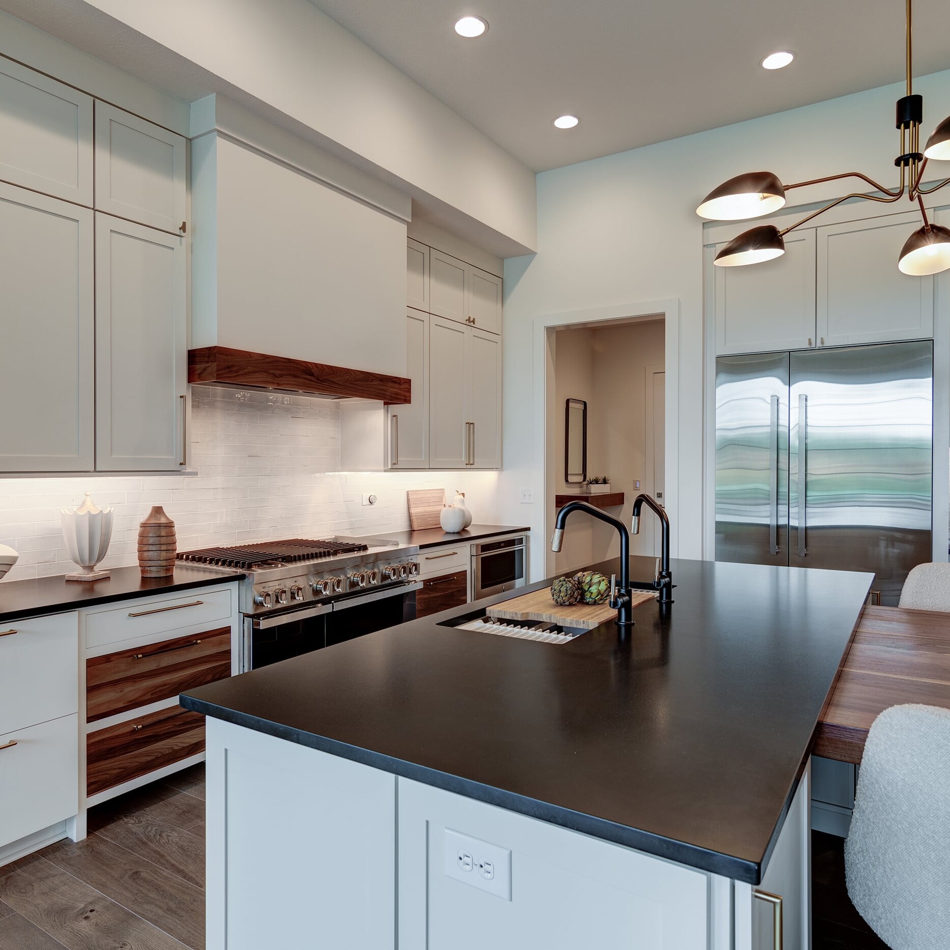 A modern kitchen with white cabinets and black counter tops.