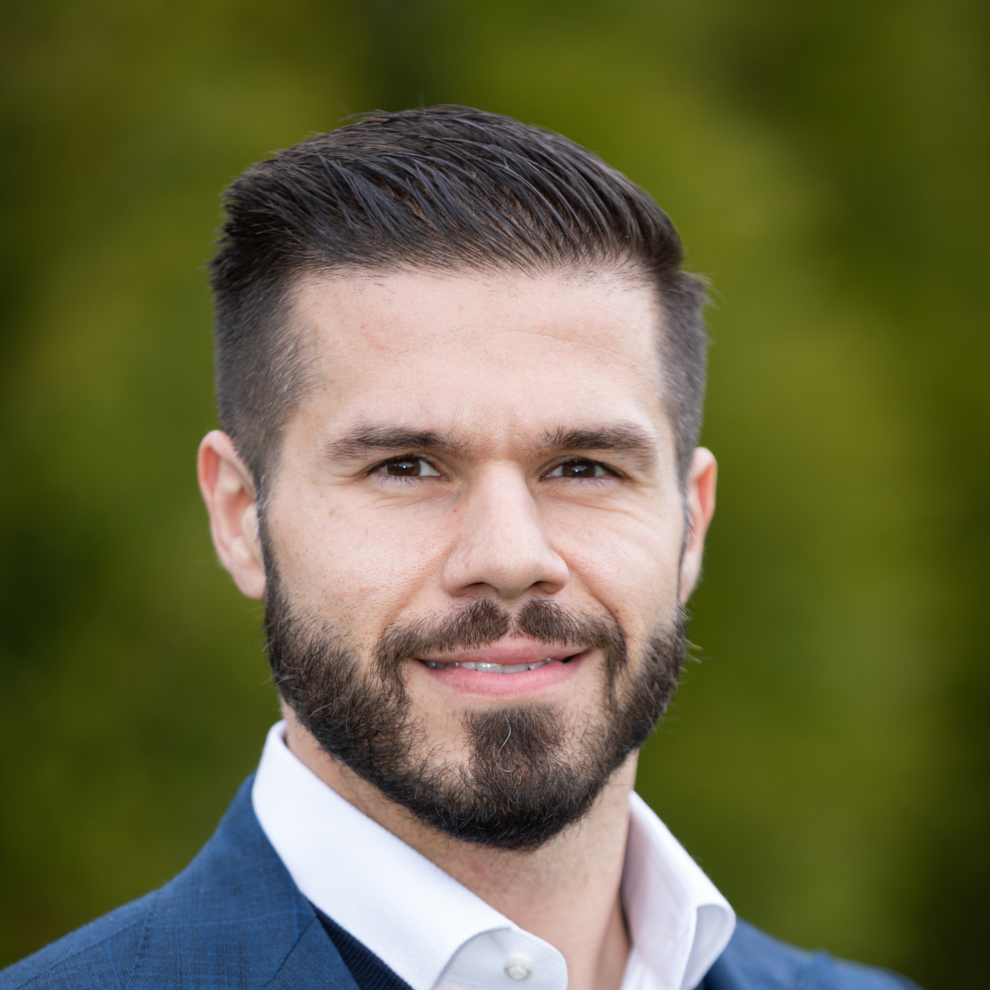 A man with a beard is smiling for the camera in front of one of the new homes built by an Indianapolis Custom Homes custom home builder in Fishers, Indiana.